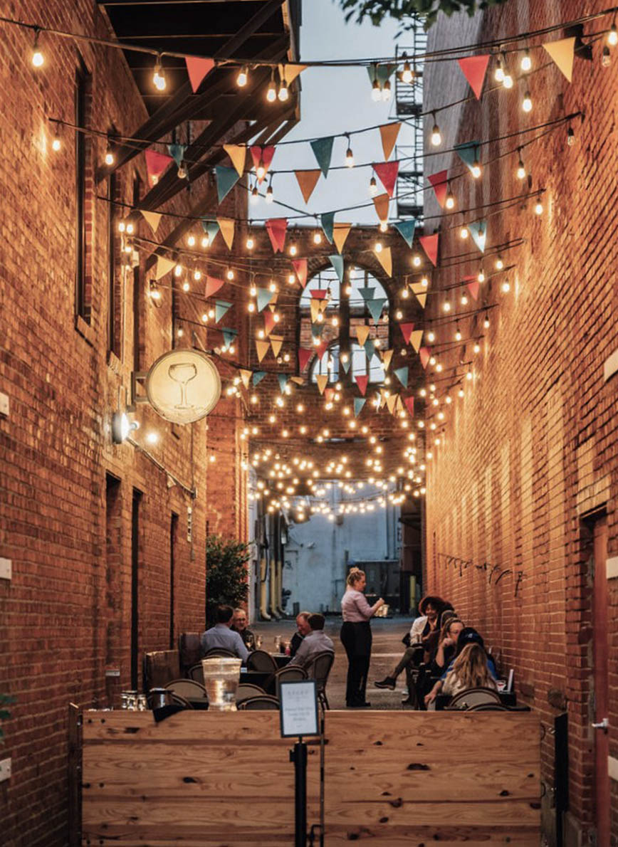 Restaurant in alley with string lights and dining tables.